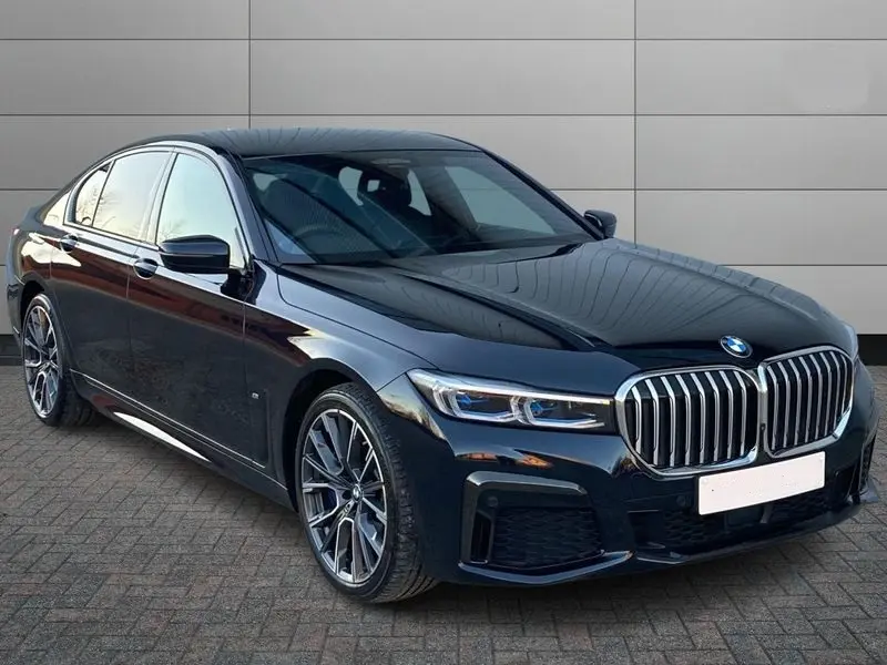 A professional chauffeur holding the door of a BMW 7 Series open.