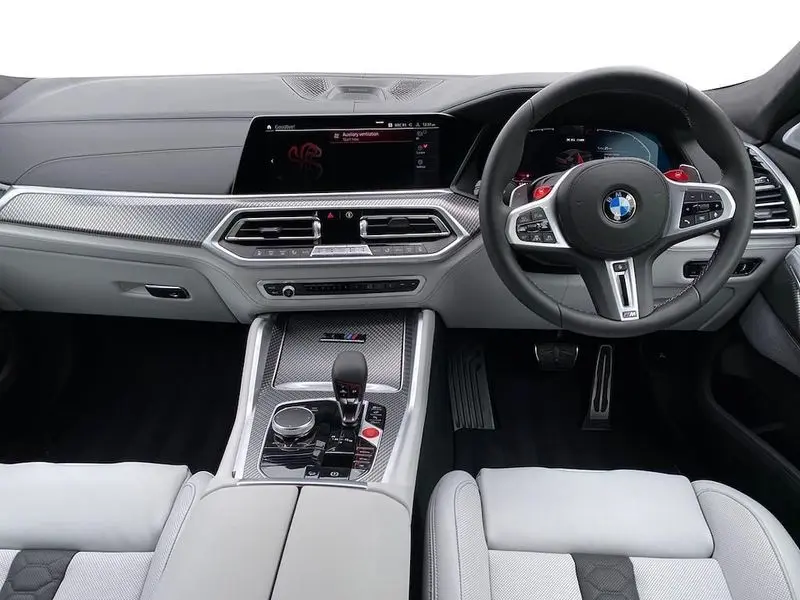 BMW X6M driving on a city street, showcasing its dynamic presence.